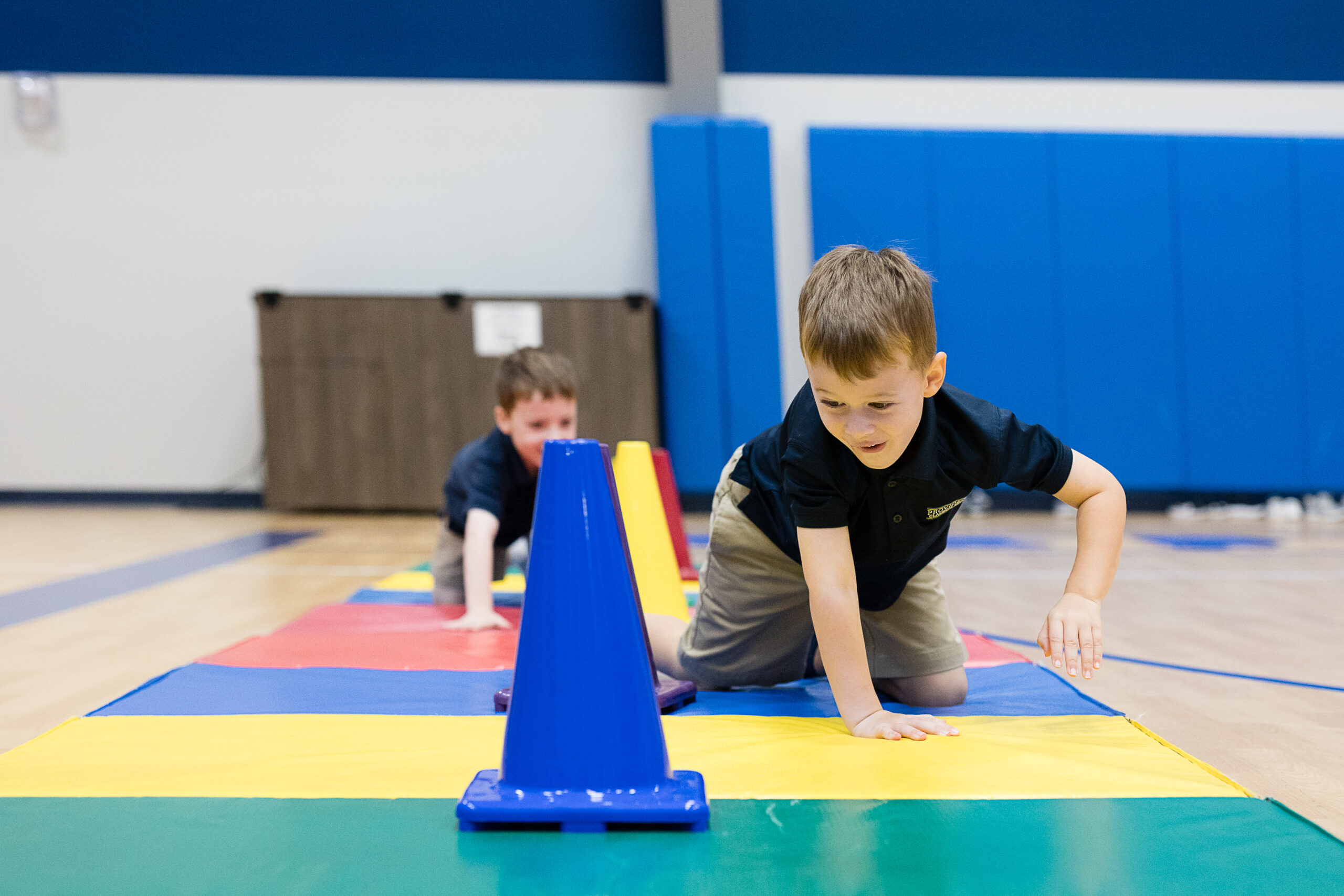 Two little boys crawl between brightly colored cones during PreK and Kindergarten Motor Lab at Providence Classical School in Spring, TX.