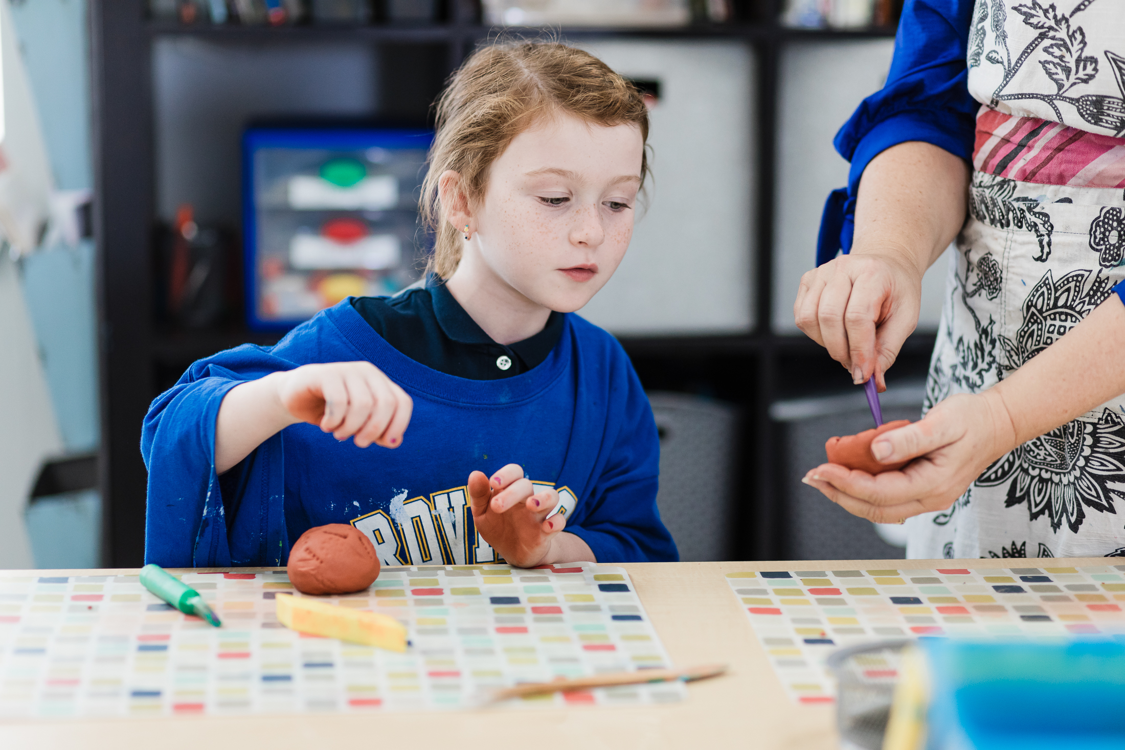 Young girl learning sculpture art with the guidance of a teacher at Providence Classical School in Spring, TX.