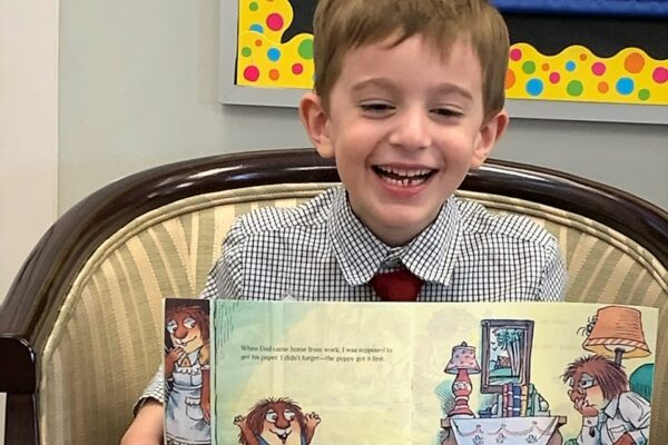 Boy reading book to class 2