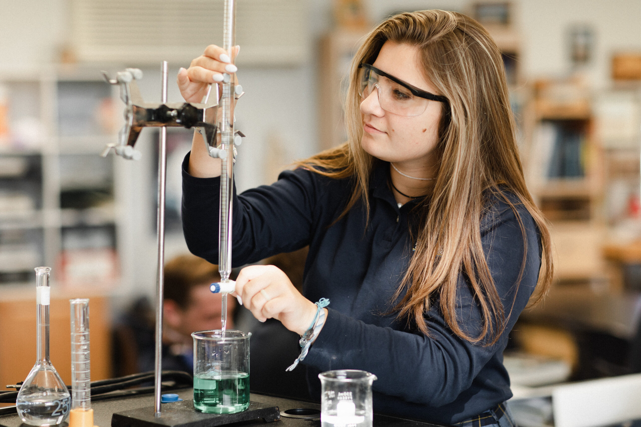 Female Chemistry student at Providence Classical School in Spring, TX titrates a green liquid