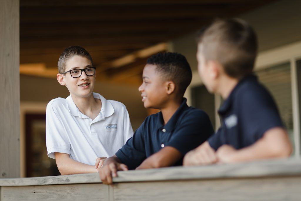 Three Providence Classical School students talking together on the school deck