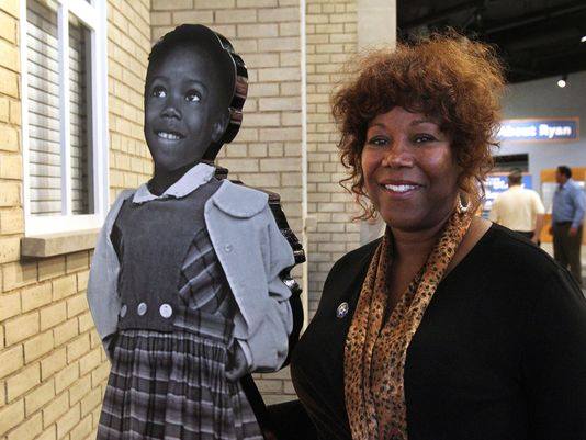 Ruby Bridges standing with her childhood photo