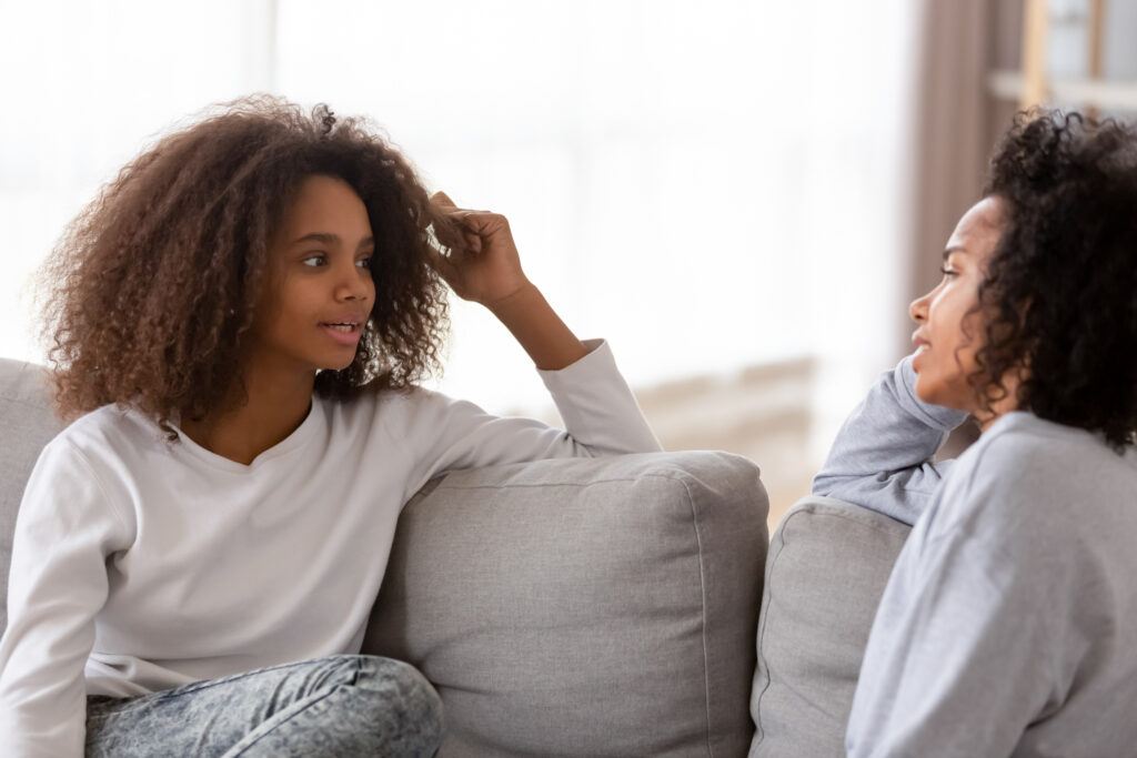 Mother listening to teenage daughter on a sofa