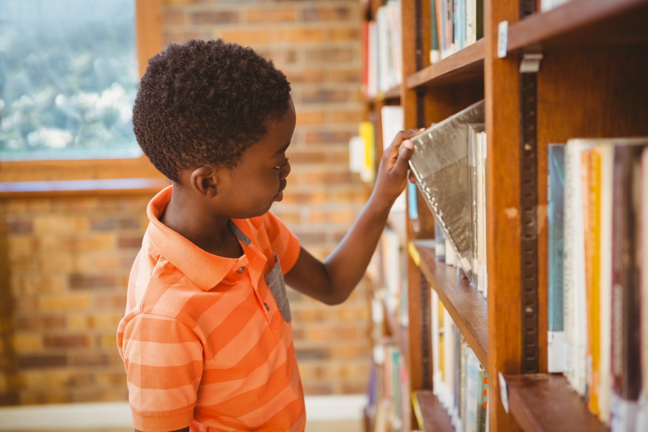 Side view of boy selecting book in library